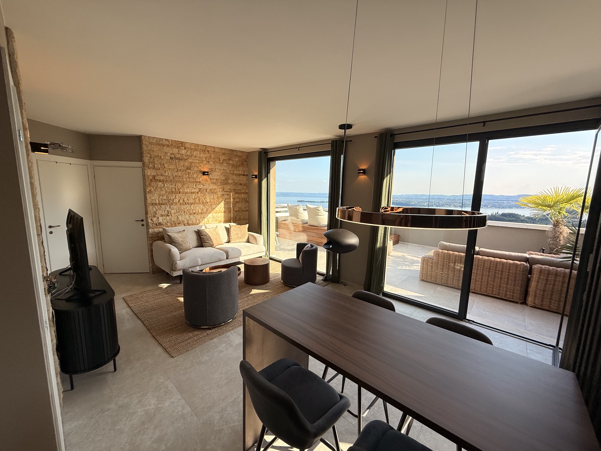Penthouse Sky Spa · M4 · Wohnbereich mit Esstisch, großer Pendelleuchte und Lago-Panorama